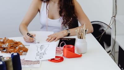 Jeune designer de mode créant des croquis sur papier dans un espace de travail moderne.