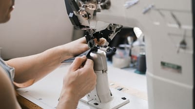 Gros plan d'un artisan du cuir au travail avec une machine à coudre industrielle.