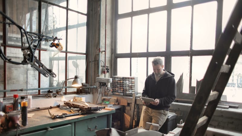 Technicien dans un atelier industriel utilisant une tablette pour la gestion du travail technique.