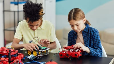 Deux adolescents collaborant sur un projet de robotique, se concentrant sur les circuits et l'innovation.