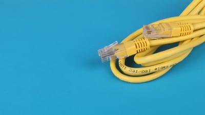 Gros plan d'un câble Ethernet jaune avec des connecteurs sur un fond bleu.