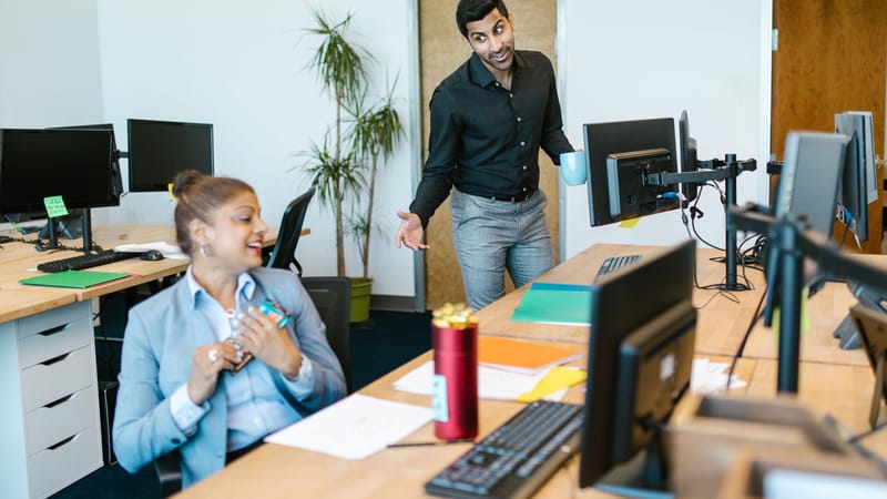 Deux collègues engageant une conversation joyeuse dans un bureau moderne.