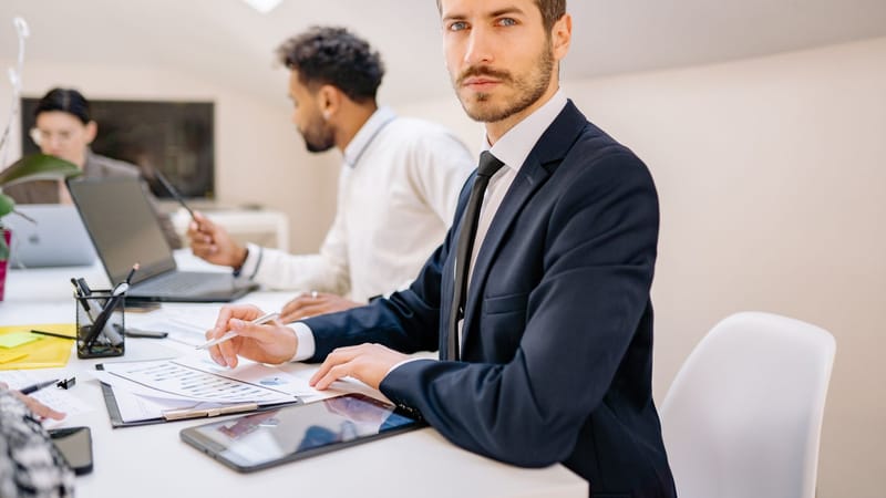 Un homme d'affaires confiant travaillant avec une équipe dans un bureau moderne, ambiance de travail d'équipe et de collaboration.