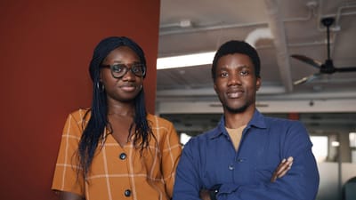 Deux professionnels confiants posant dans un environnement de bureau contemporain, incarnant le travail d'équipe et le succès.