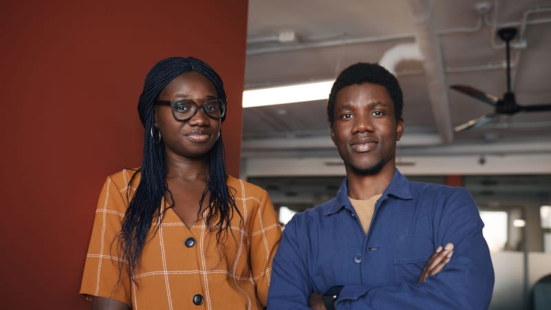 Deux professionnels confiants posant dans un environnement de bureau contemporain, incarnant le travail d'équipe et le succès.