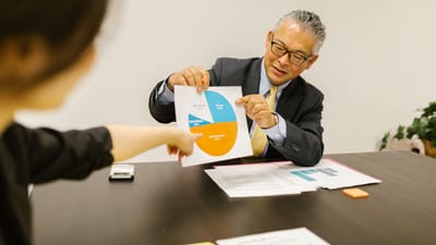 Environnement professionnel avec des collègues discutant des graphiques lors d'une réunion d'affaires.