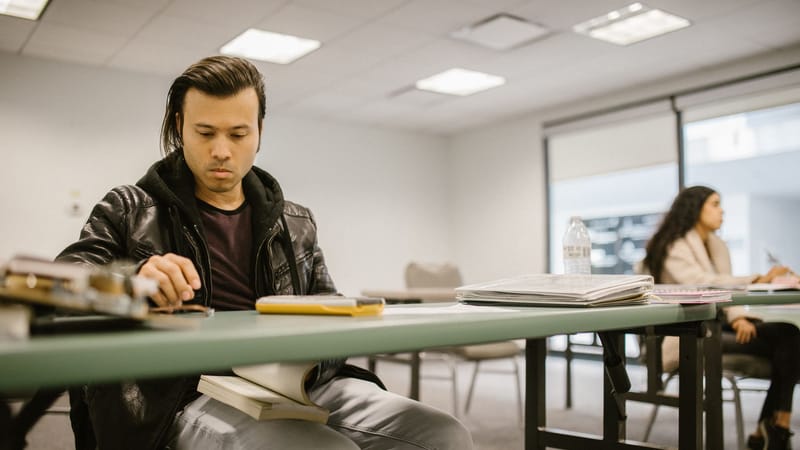 Deux étudiants universitaires engagés dans une étude concentrée à un bureau de classe, se préparant pour les examens.