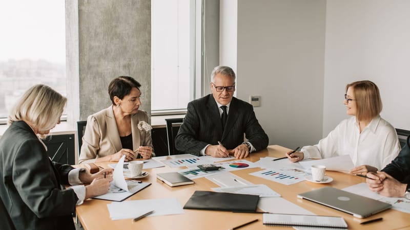 Un groupe de professionnels discutant de documents d'affaires lors d'une réunion dans un bureau moderne.