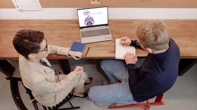 Deux adultes engagés dans l'apprentissage en ligne, l'un prenant des notes pendant une session d'étude d'anglais.