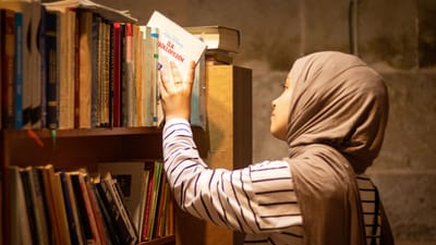 Une femme avec un foulard explore les étagères de la bibliothèque, choisissant un livre à Kayseri, en Turquie.