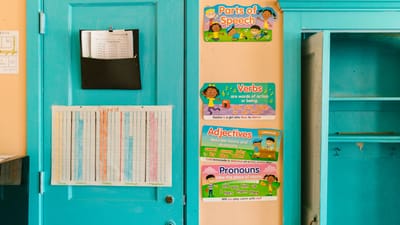 Mur de maternelle vibrant avec des affiches éducatives et une porte bleue.