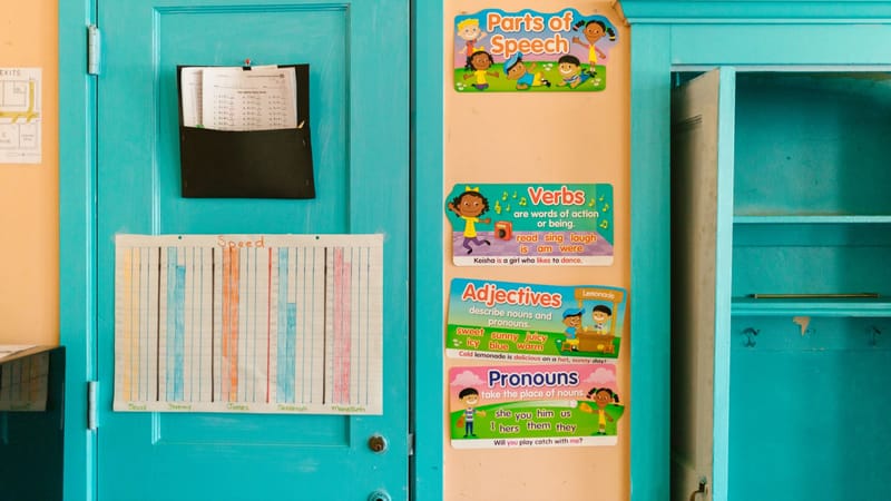 Mur de maternelle vibrant avec des affiches éducatives et une porte bleue.
