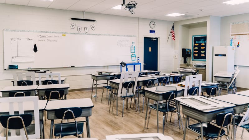 Une salle de classe vide avec des bureaux disposés, un tableau blanc et une décoration éducative, prête pour l'apprentissage.