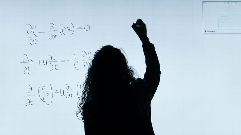 Une silhouette de femme écrivant des équations mathématiques sur un grand tableau blanc, représentant l'éducation et l'analyse.