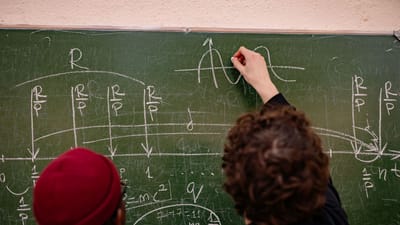 Des étudiants travaillant ensemble sur des problèmes mathématiques complexes sur un tableau noir.