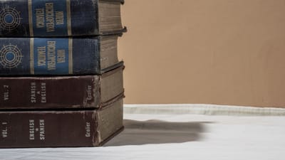 Une pile d'anciennes encyclopédies et dictionnaires avec de l'espace pour le texte sur un fond neutre.