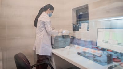 Femme en blouse de laboratoire examine des équipements dans un environnement de laboratoire, Bakou, Azerbaïdjan.