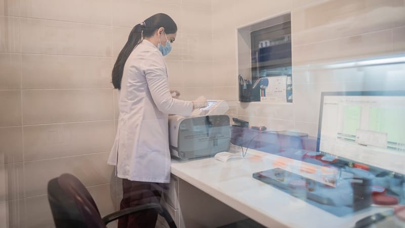 Femme en blouse de laboratoire examine des équipements dans un environnement de laboratoire, Bakou, Azerbaïdjan.