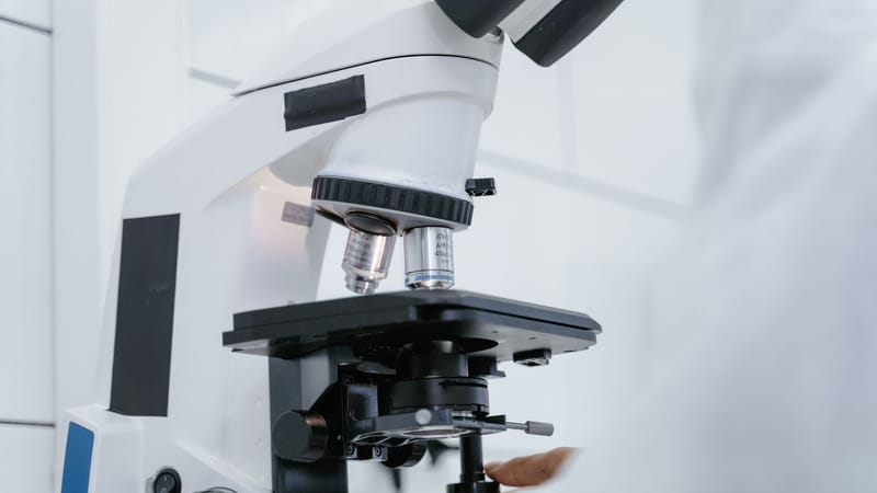 Vue détaillée d'un scientifique utilisant un microscope dans un laboratoire.