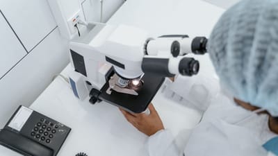 Un scientifique en blouson de laboratoire observé utilisant un microscope pour la recherche.
