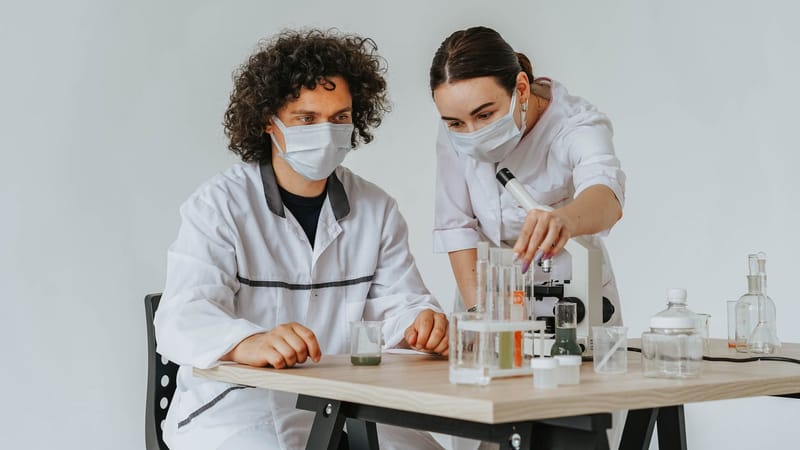 Deux scientifiques travaillant sur des expériences dans un laboratoire avec des microscopes et des éprouvettes.