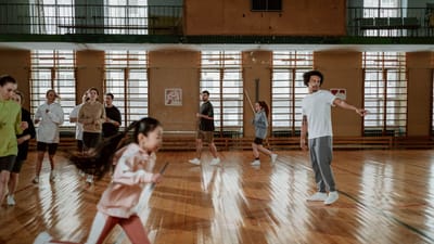 Un groupe diversifié de personnes courant et s'entraînant sur un terrain de basketball intérieur avec un sol en bois.