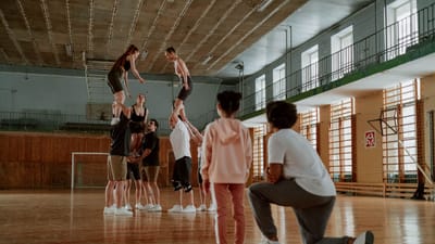 Groupe d'athlètes répétant des mouvements de cheerleading en intérieur.