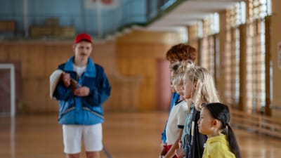 Groupe divers d'enfants se tenant à l'intérieur d'un gymnase avec un entraîneur en focus.