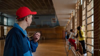 Un entraîneur guide de jeunes étudiants lors d'une séance d'éducation physique dans un gymnase intérieur.