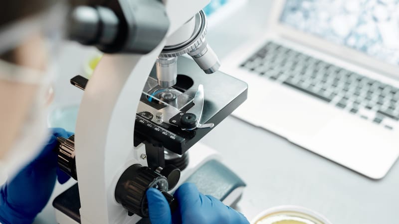 Chercheur analysant des échantillons biologiques sous un microscope dans un laboratoire.