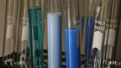 Gros plan sur des solutions chimiques colorées dans des tubes à essai en verre, en laboratoire.