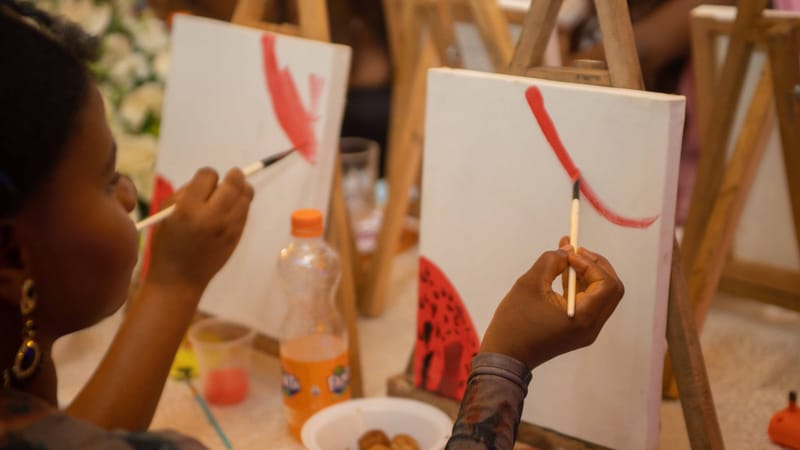 Des personnes de tous horizons apprécient une séance de peinture en groupe avec pinceaux et toiles.
