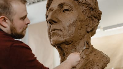 Gros plan d'un sculpteur façonnant méticuleusement un buste en argile avec un outil de boucle dans un studio.