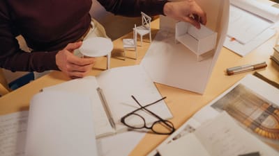 Architecte travaillant sur des modèles de meubles miniatures dans un espace créatif. Accent sur le processus de design fait main.