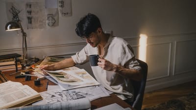 Un architecte créatif travaillant chez lui, examinant des plans avec un café.