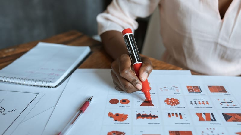 Gros plan sur une personne marquant des graphiques d'affaires avec un marqueur rouge, illustrant l'analyse de données et la planification.