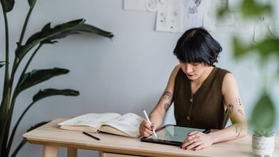 Une femme asiatique concentrée sur la création d'art numérique dans un espace de travail moderne.