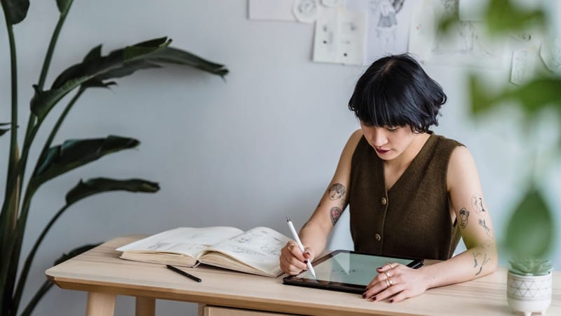 Une femme asiatique concentrée sur la création d'art numérique dans un espace de travail moderne.