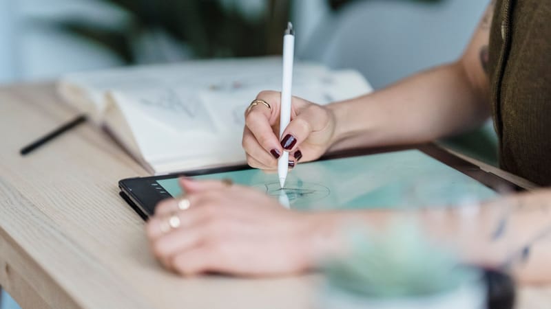 Artiste féminine concentrée esquissant sur une tablette numérique, stimulant la créativité dans un studio moderne.