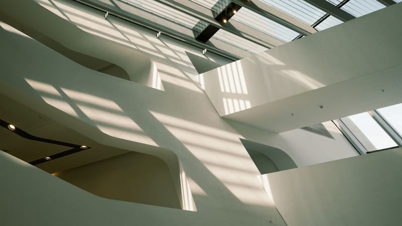 Architecture intérieure minimaliste avec des lucarnes et des ombres géométriques, parfaite pour l'inspiration design.