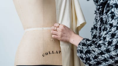 Un designer de mode ajuste un tissu sur un mannequin, travaillant avec soin dans un environnement de studio.