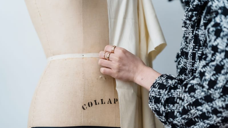 Un designer de mode ajuste un tissu sur un mannequin, travaillant avec soin dans un environnement de studio.