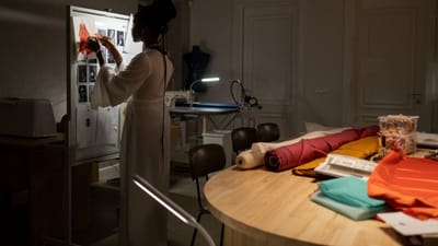 Designer de mode organisant un mood board dans un espace de travail faiblement éclairé avec des tissus.