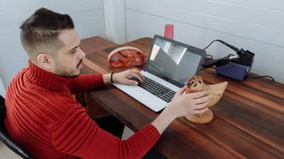 Ingénieur travaillant sur un ordinateur portable à un bureau en bois, tenant un modèle 3D dans un cadre de bureau.