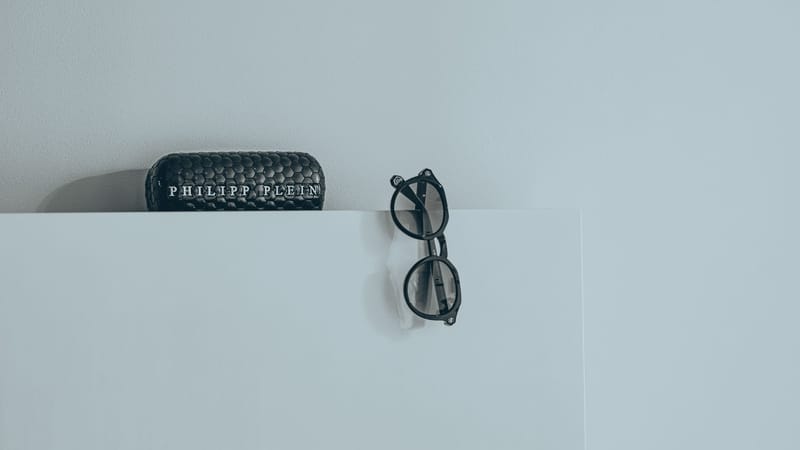 Gros plan sur des lunettes noires élégantes avec un étui de designer texturé sur fond blanc.