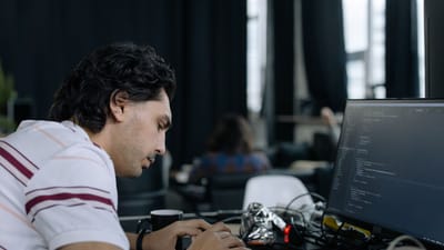 Un développeur tapant intensément à un poste de travail dans un bureau contemporain.