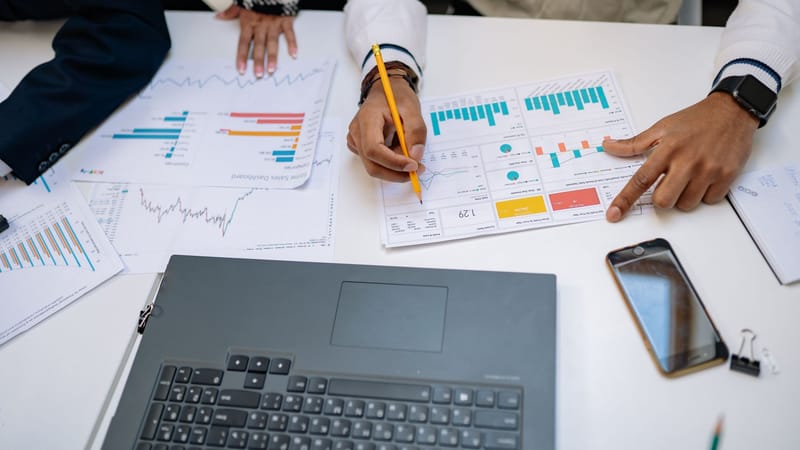 Équipe de professionnels travaillant sur des rapports financiers en utilisant des graphiques et des dispositifs.