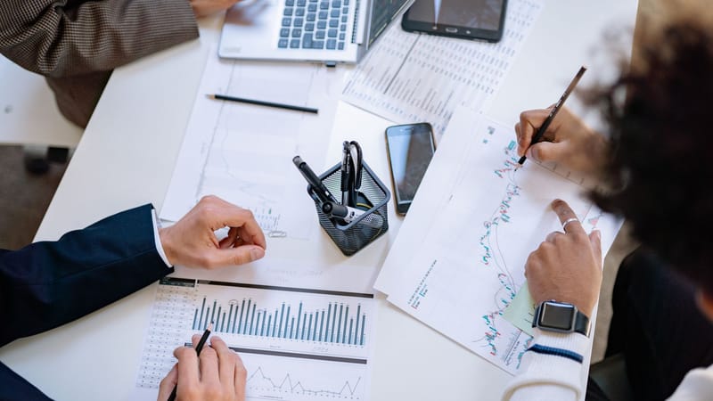 Équipe commerciale analysant des graphiques et des tableaux financiers lors d'une réunion collaborative.