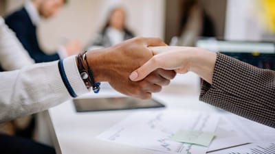 Des professionnels divers échangent une poignée de main dans un environnement de bureau, symbolisant un accord.