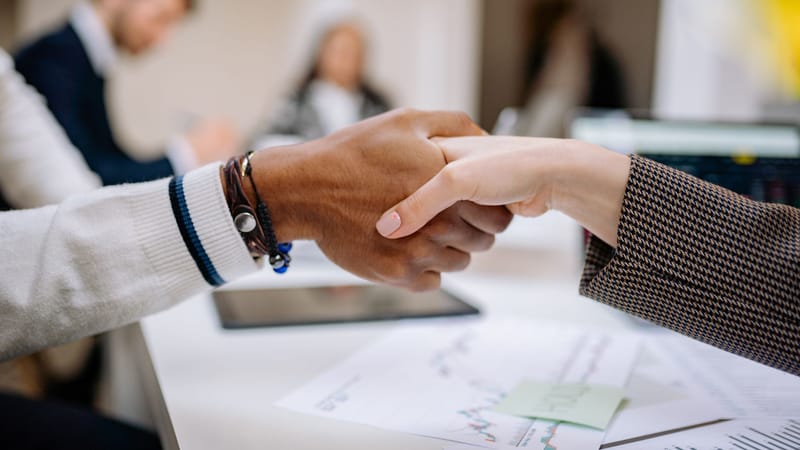 Des professionnels divers échangent une poignée de main dans un environnement de bureau, symbolisant un accord.